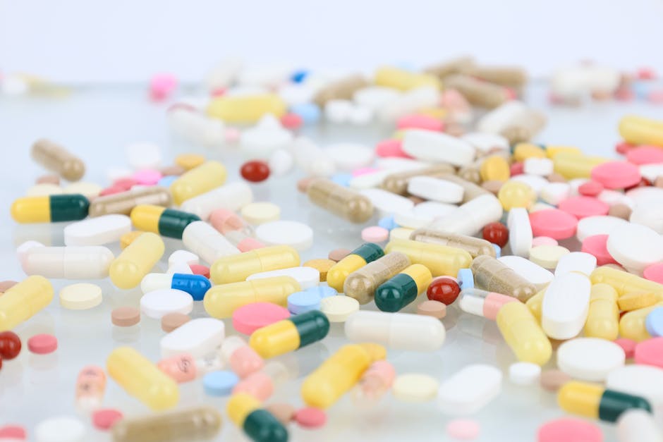A vibrant assortment of pills and capsules scattered across a white surface representing medication and healthcare.