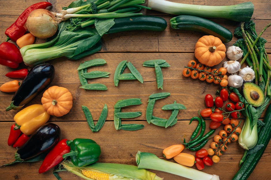A vibrant flat lay of various fresh vegetables spelling 'Eat Veg' on a wooden background.