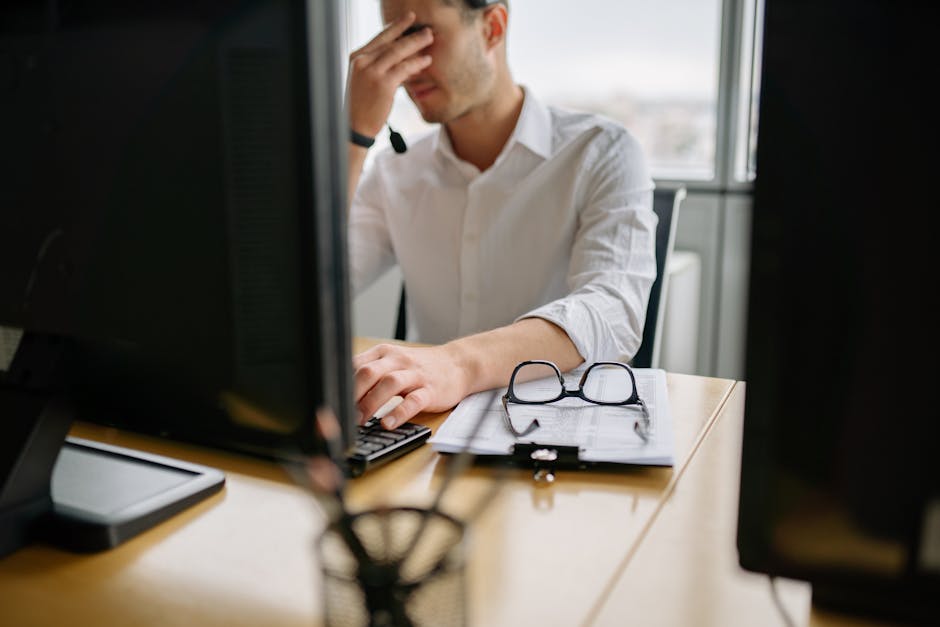 Man at office desk holding head in frustration, signifying stress at work.