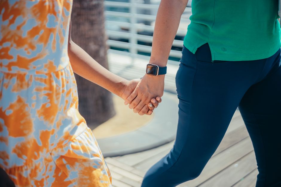 Close-up of a couple holding hands outdoors, emphasizing connection and warmth on a bright day.