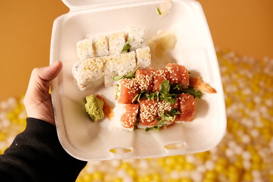 Vibrant sushi takeout with assorted rolls in a foam container, ready to enjoy.
