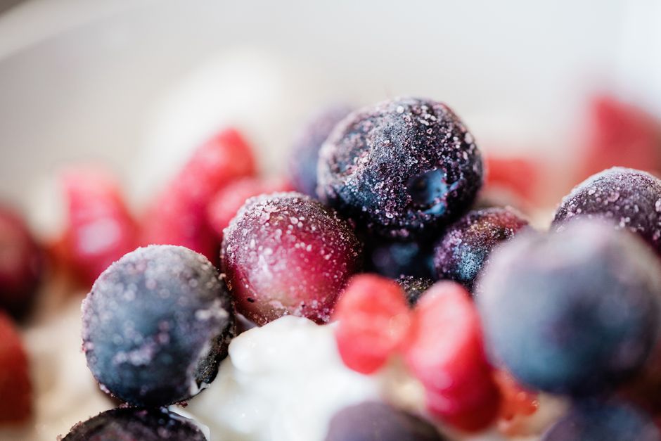 Delicious close-up of colorful frozen berries topped on a creamy dessert, perfect for food inspirations.